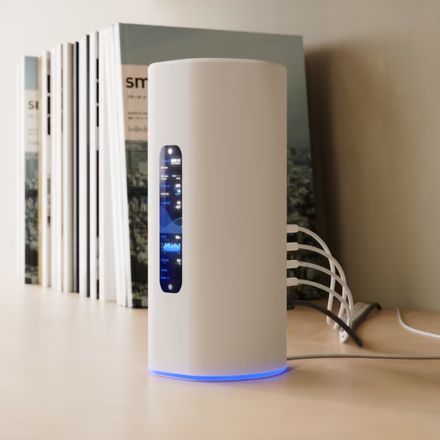 Passerelle UniFi tout-en-un posée sur une étagère, petit écran affichant les statistiques du réseau et cordons Ethernet raccordés à l'arrière.
